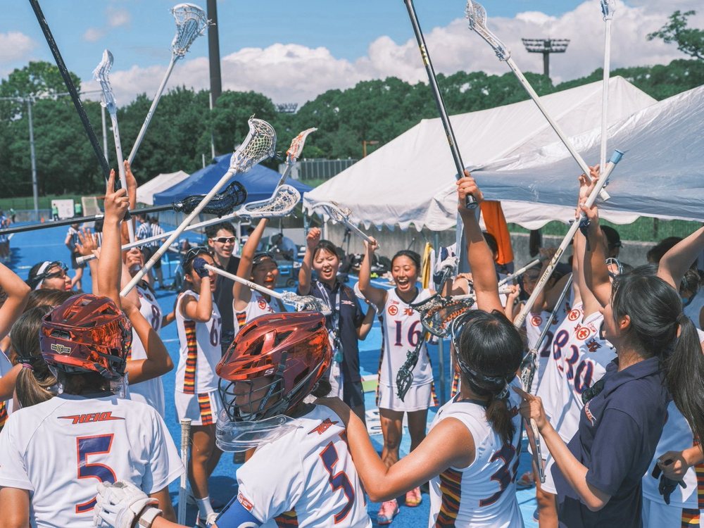 勝利の後にクロスを高く掲げる女子部の選手たち